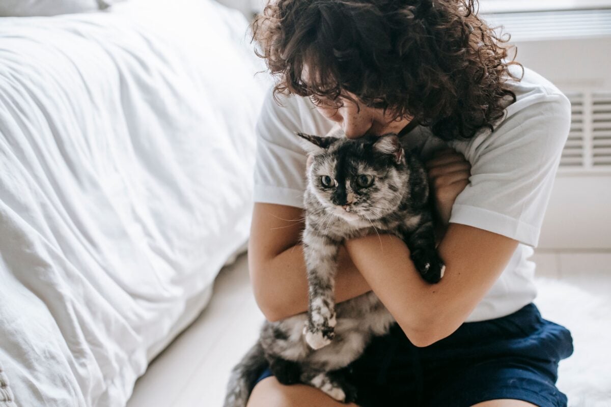 Woman holding a cat whose eyes look irritated.